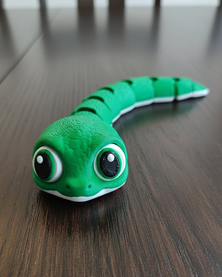 Bébé serpent articulé sur un bureau près d'une petite plante