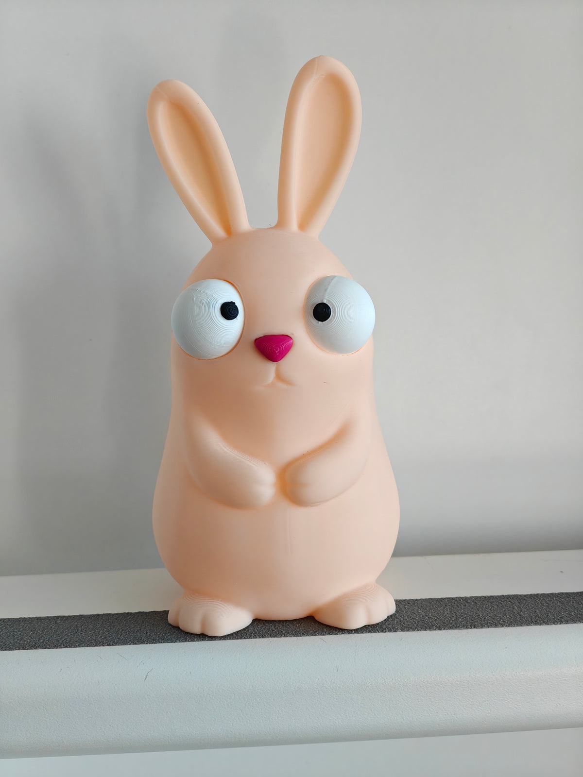 Figurine de lapin de Pâques rigolote aux grands yeux mobiles sur fond blanc