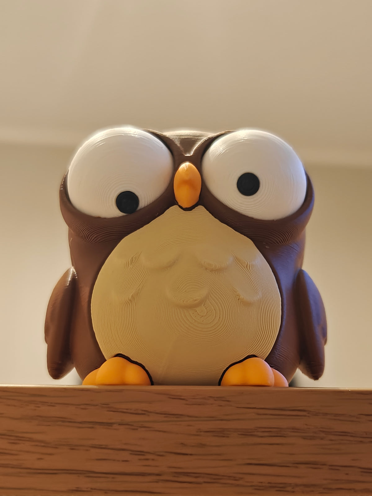 Hibou de dessin animé sur un bureau en bois à côté d'une petite plante