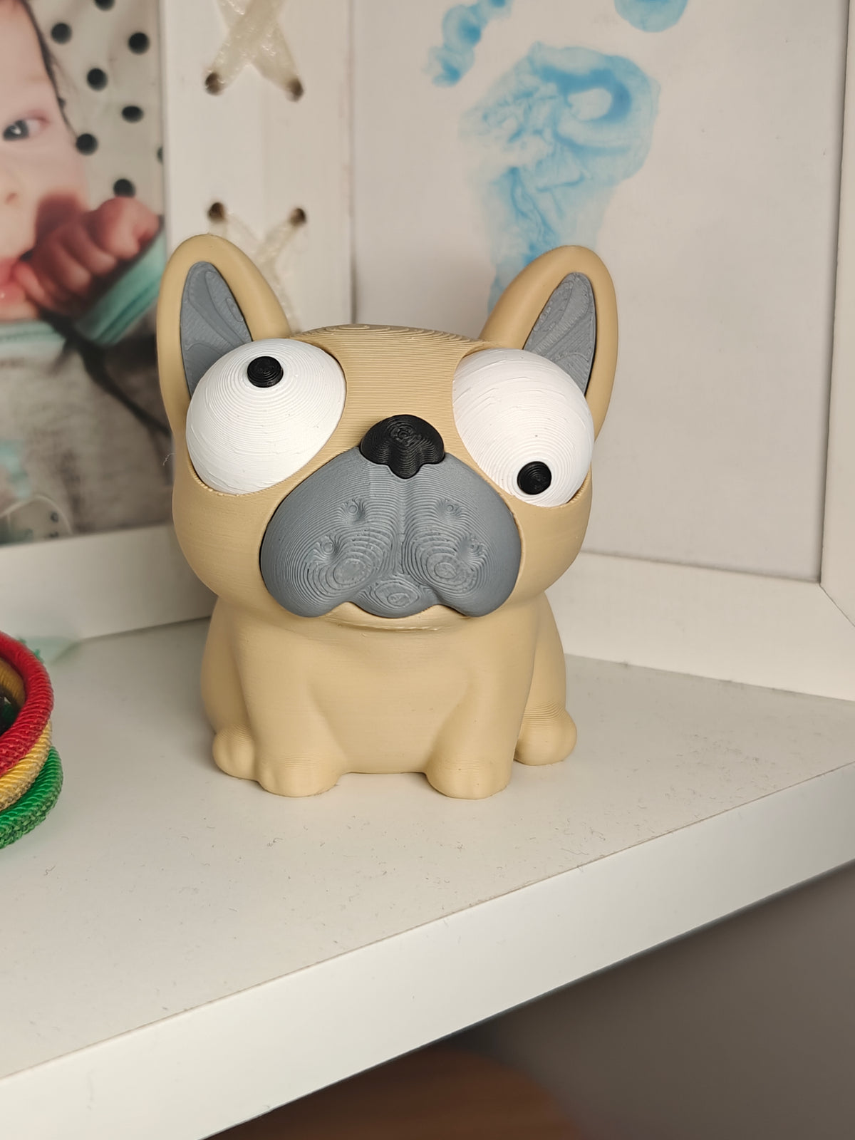 Figurine de bouledogue français rigolote sur un bureau près d'un clavier et d'une plante