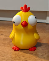 Gros plan d'une figurine de poussin amusante aux grands yeux mobiles sur fond blanc