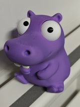 Figurine d'hippopotame rigolote aux yeux mobiles sur un bureau près d'une tasse à café