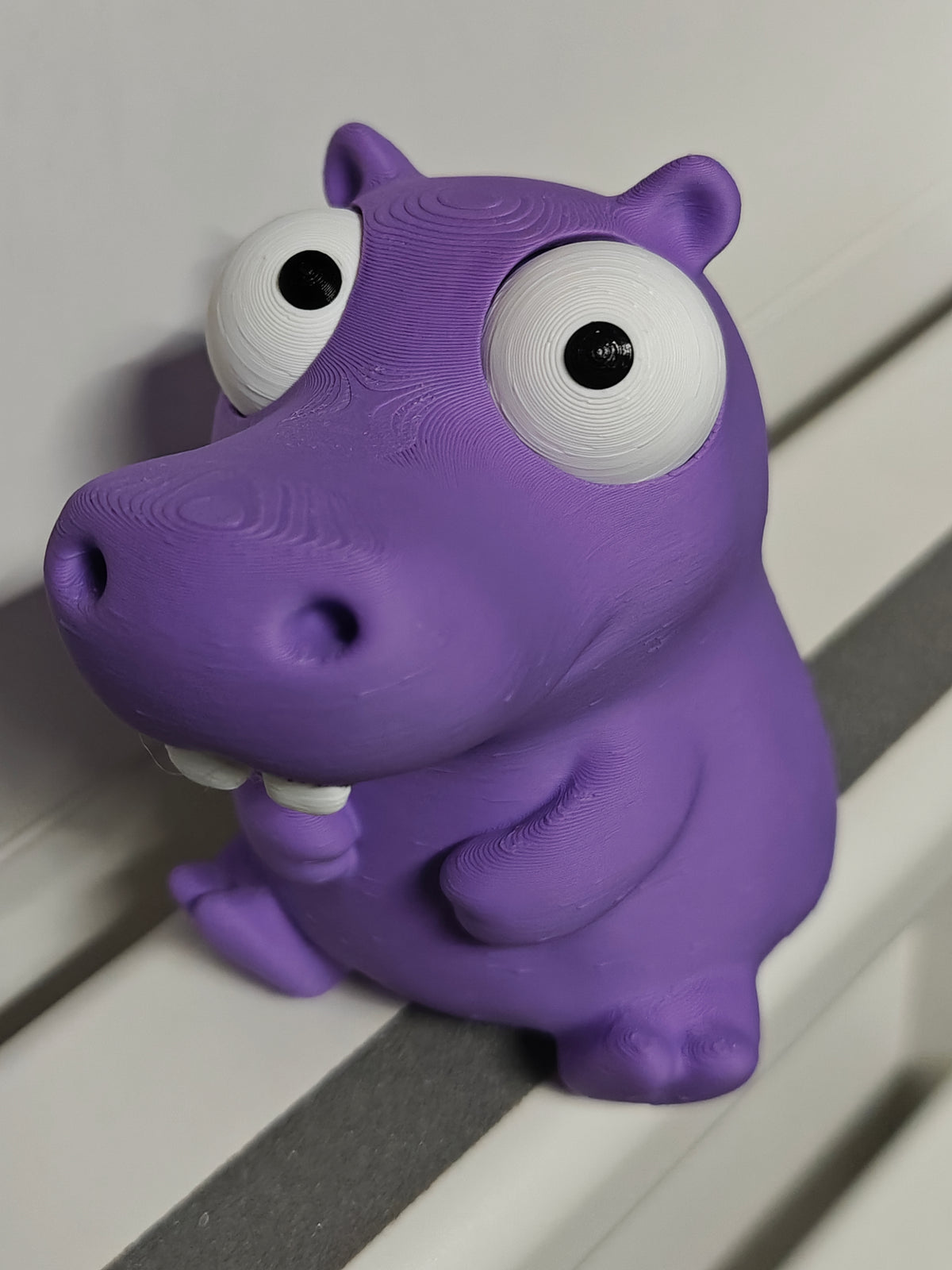 Figurine d'hippopotame rigolote aux yeux mobiles sur un bureau près d'une tasse à café