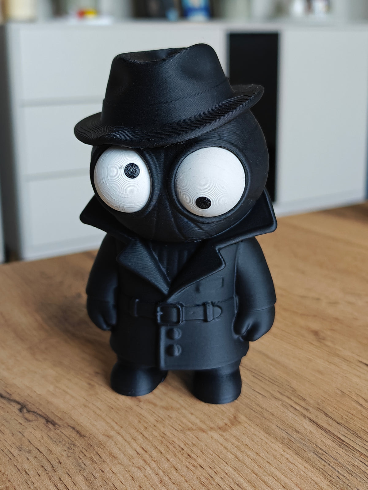 Figurine Spider Noir aux yeux mobiles, manteau sombre et chapeau, gros plan sur fond blanc