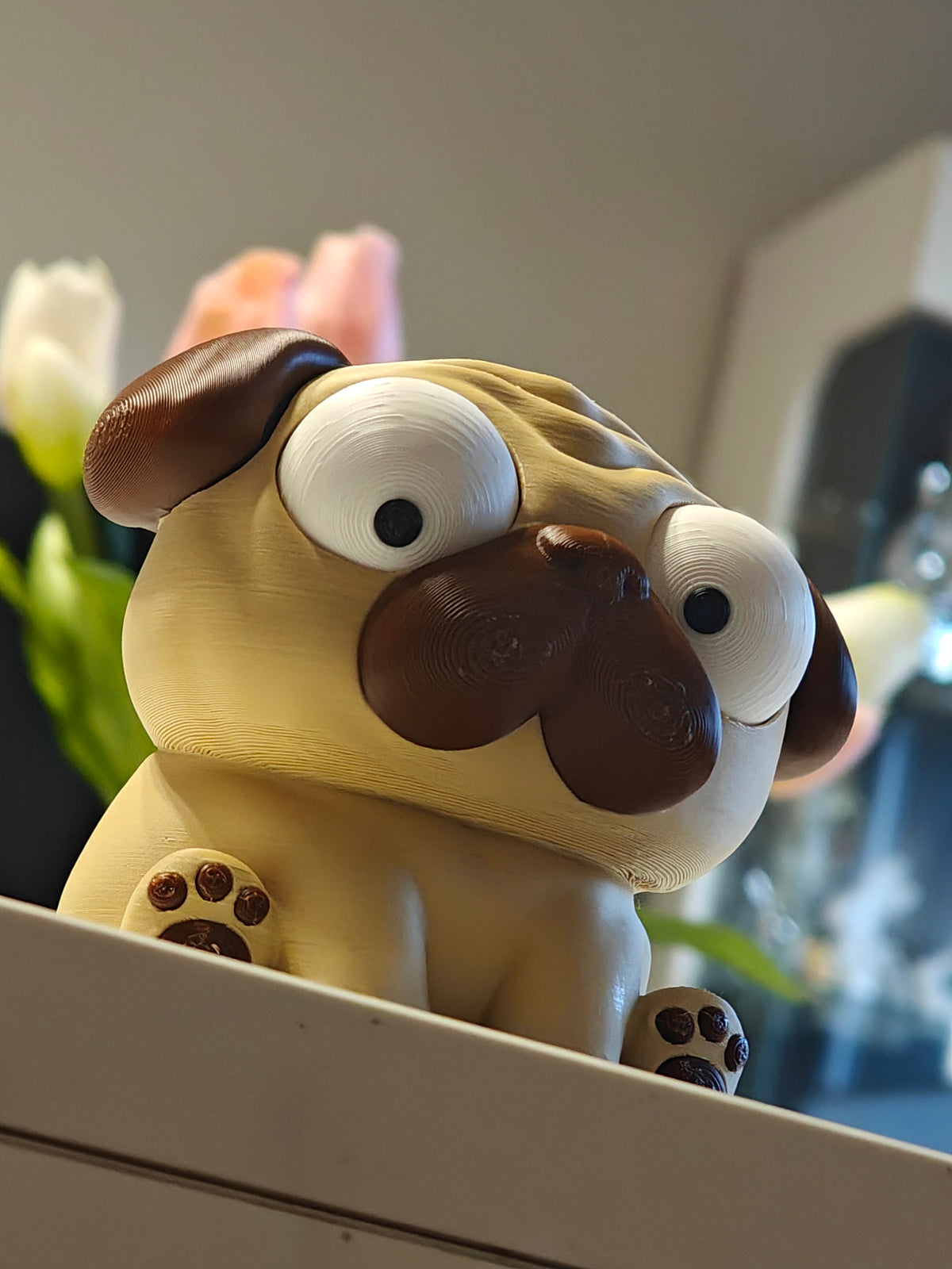 Figurine de carlin aux yeux mobiles sur fond blanc – jouet de bureau Puggy