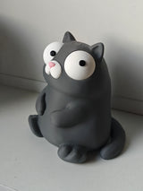 Figurine de chat rigolote aux yeux mobiles sur un bureau près d'un mug