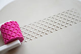 Rouleau à texture avec poignée pour céramique sur une surface blanche avec détail du motif