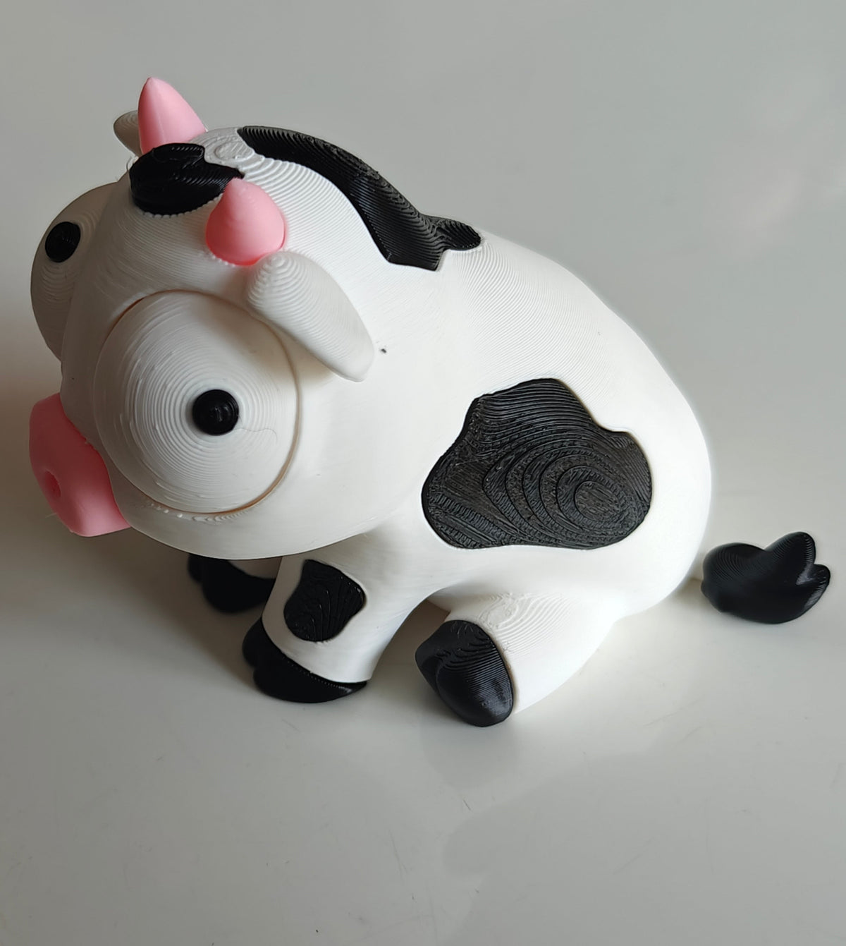 Gros plan d'une figurine de vache blanche et noire amusante aux grands yeux mobiles