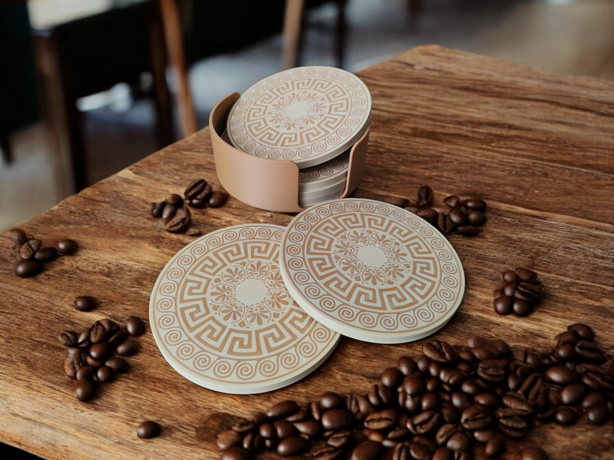 Six sous-verres à motif grec empilés dans leur support assorti sur une table en bois