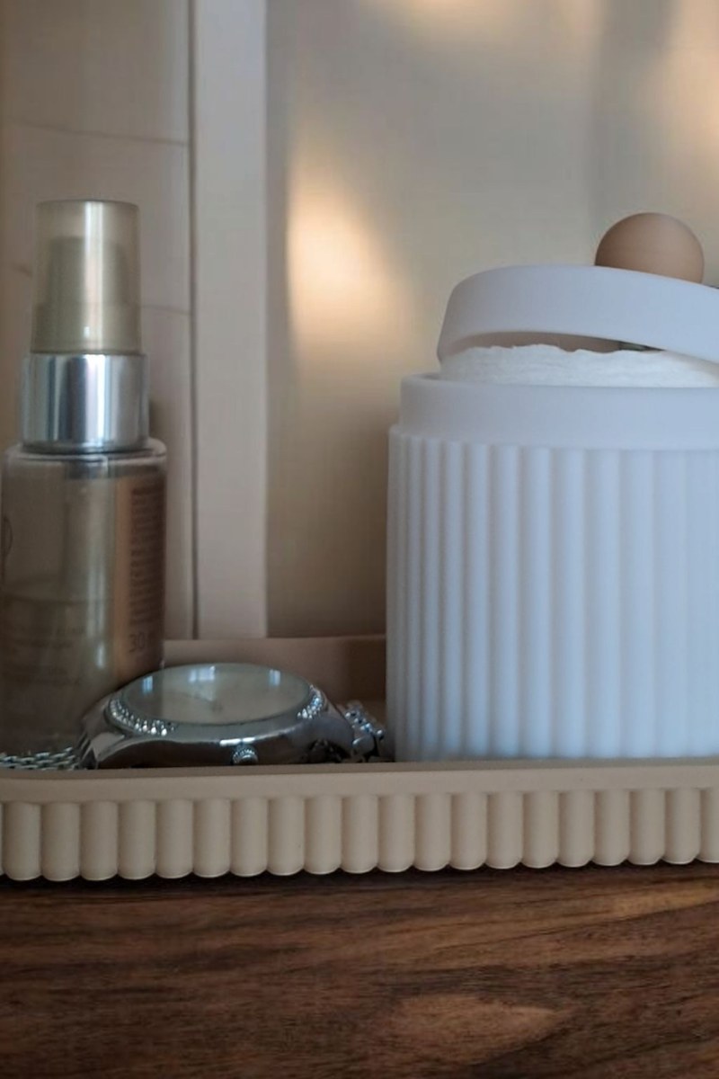 Gros plan d'un pot à bijoux cannelé avec couvercle et plateau assorti, rose et blanc