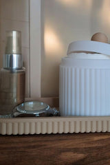 Gros plan d'un pot à bijoux cannelé avec couvercle et plateau assorti, rose et blanc