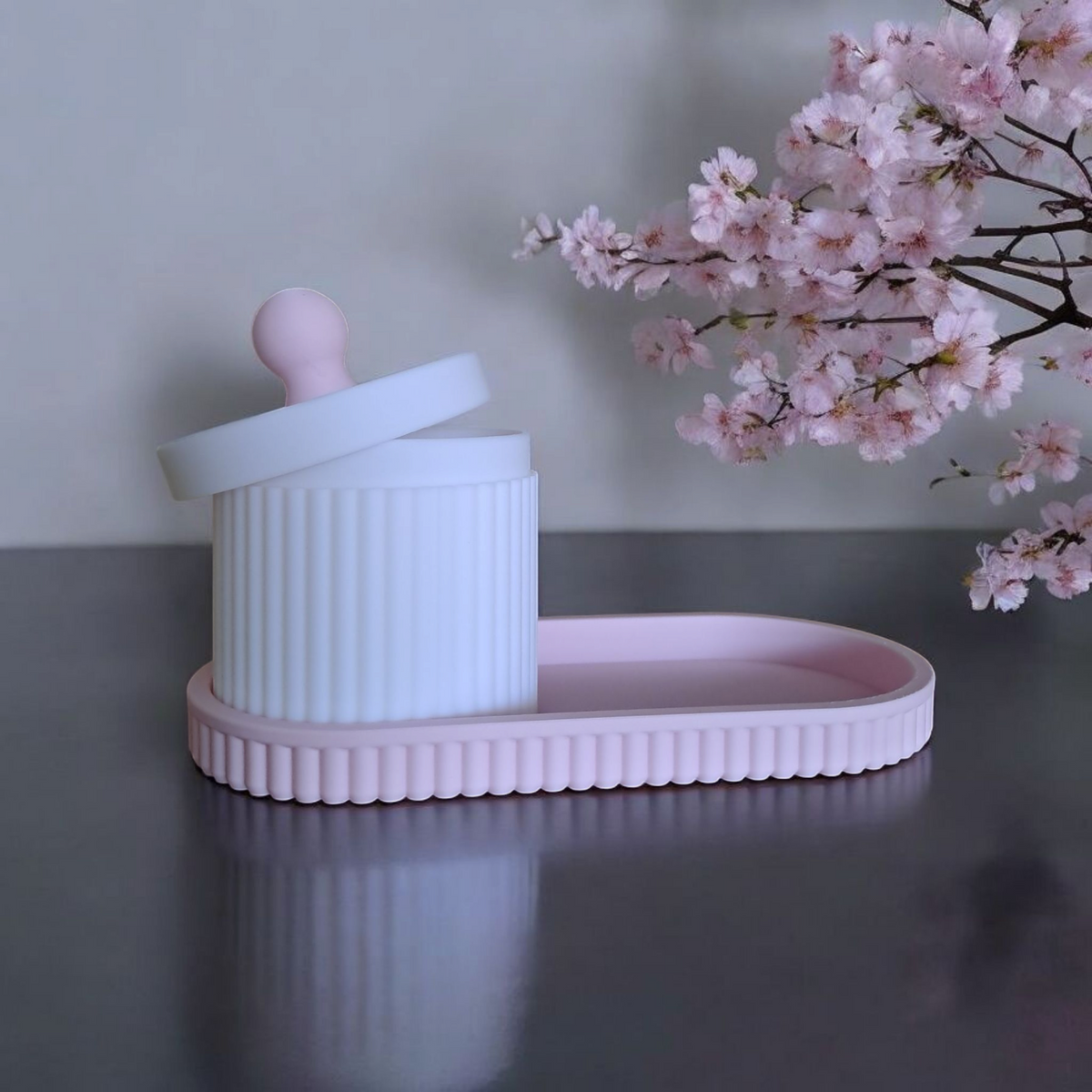 Gros plan d'un pot à bijoux cannelé avec couvercle et plateau assorti, rose et blanc