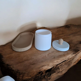 Gros plan d'un pot à bijoux cannelé avec couvercle et plateau assorti, rose et blanc