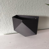 Pot mural low poly fixé sur un mur blanc avec une petite plante en pot