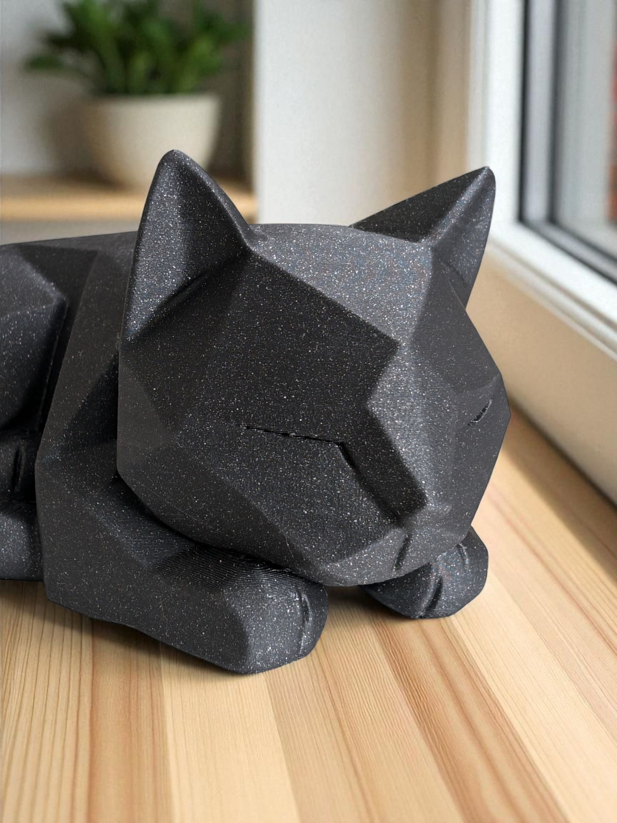 Détail des facettes anguleuses sur la tête et le corps de la figurine de chat qui attend