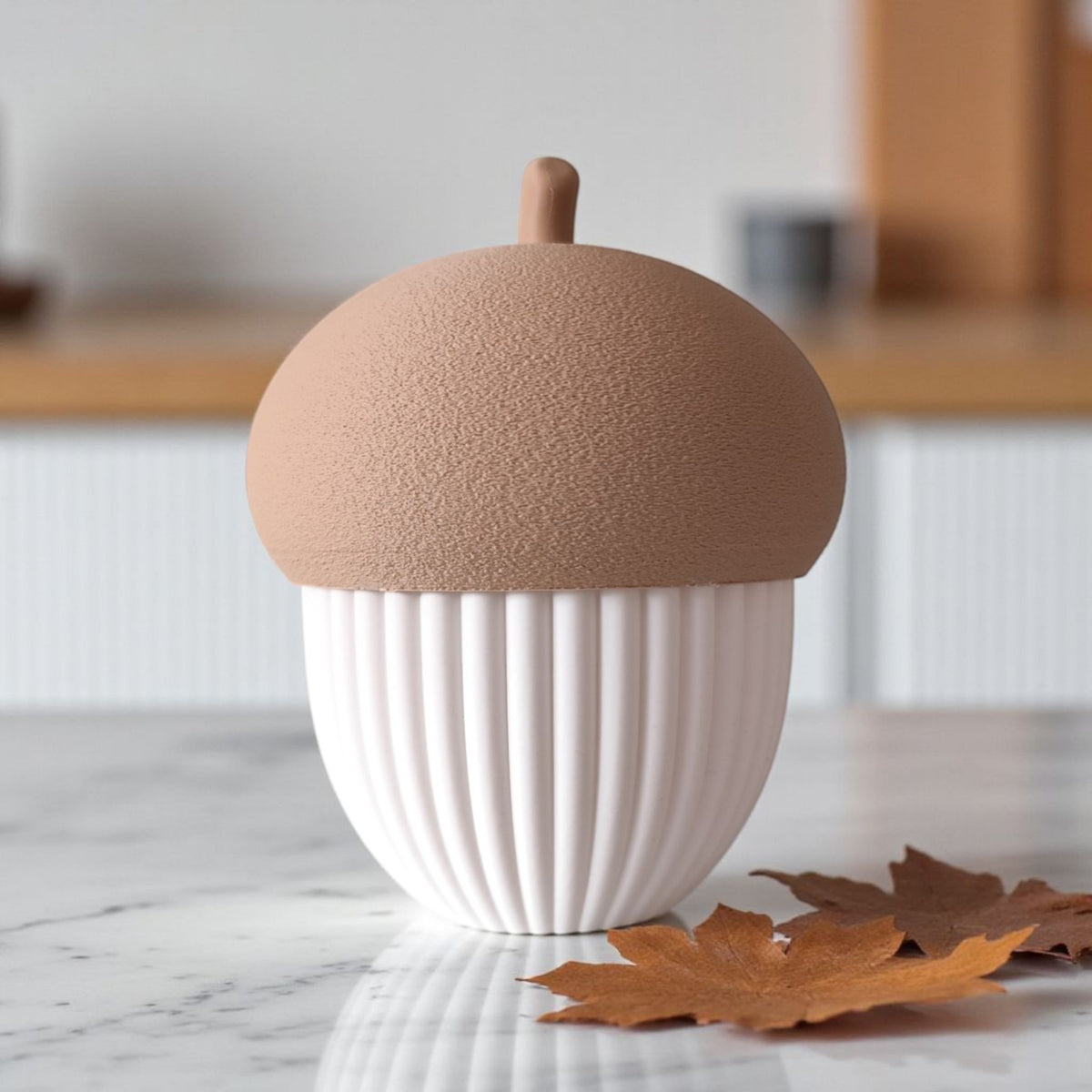 Boîte striée en forme de gland sur une étagère avec une déco automnale et une lumière chaude