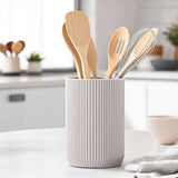 Pot à ustensiles strié sur le plan de travail avec des cuillères en bois et des spatules