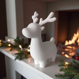 Renne de Noël minimaliste sur un rebord de fenêtre blanc à la lumière naturelle