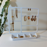 Porte-bijoux mural au-dessus d'une commode avec boucles d'oreilles et colliers fins