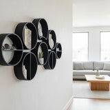Trois étagères rondes modulaires alignées verticalement sur un mur blanc avec de petits objets