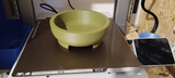 Pot à bonsaï rond sur une étagère en bois avec une petite plante