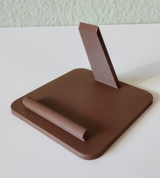 Support de téléphone sur un bureau près d'une lampe et d'un carnet, téléphone bien incliné pour la lecture