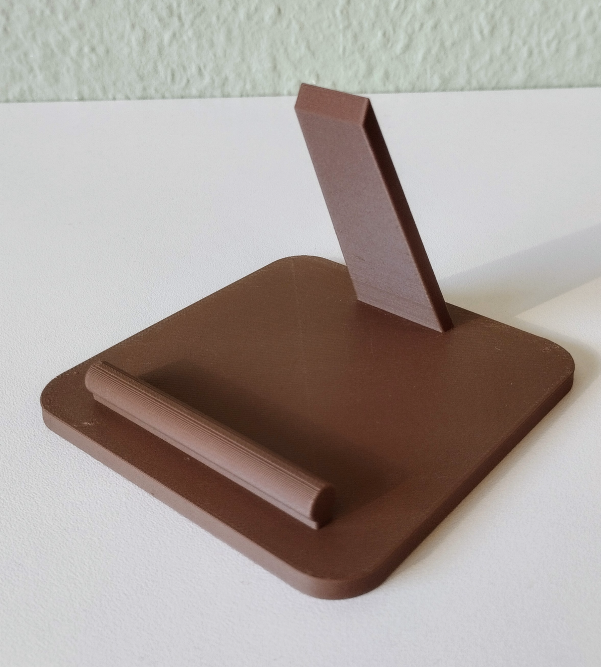 Support de téléphone sur un bureau près d'une lampe et d'un carnet, téléphone bien incliné pour la lecture
