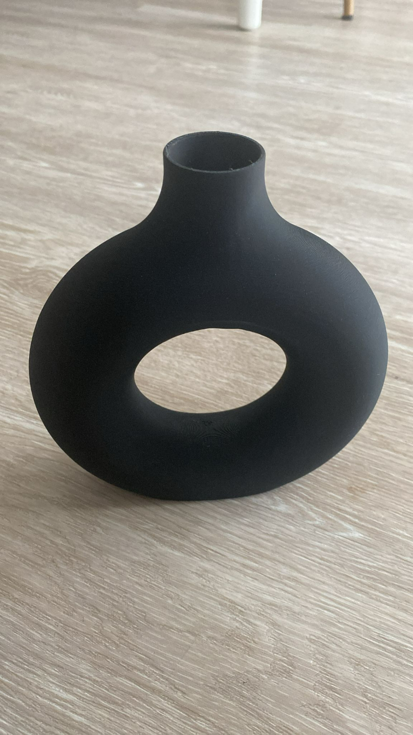 Détail de l'ouverture ronde du vase à la forme creuse géométrique et à la surface lisse