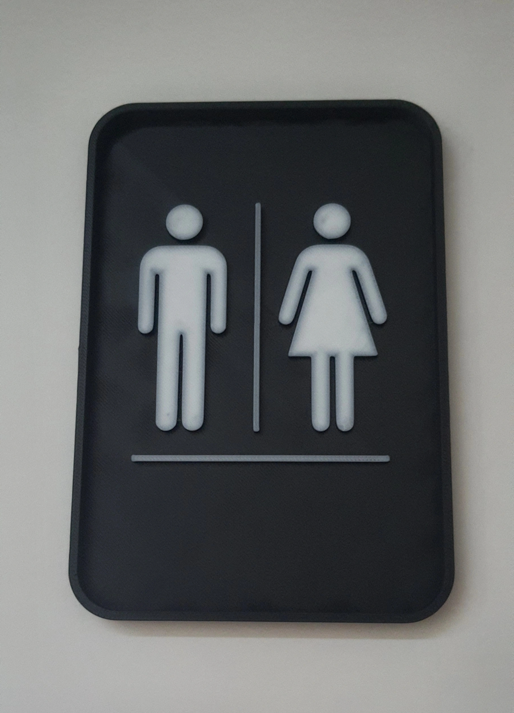 Détail de la typographie nette et de la finition neutre de la plaque de toilettes