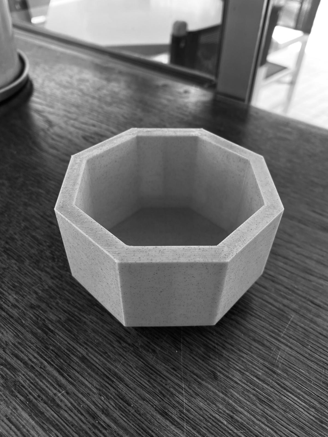 Cache-pot octogonal sur une étagère blanche avec une petite plante grasse