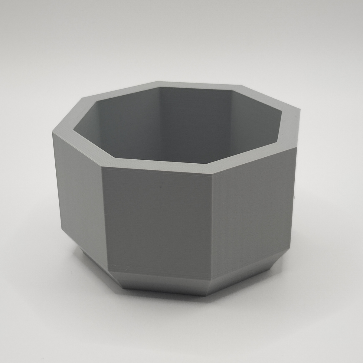 Détail du bord octogonal d'un pot de fleurs minimaliste sous une lumière douce