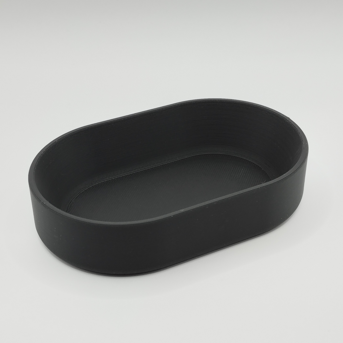 Plateau ovale sur une table d'entrée avec des clés, des pièces et une déco minimaliste