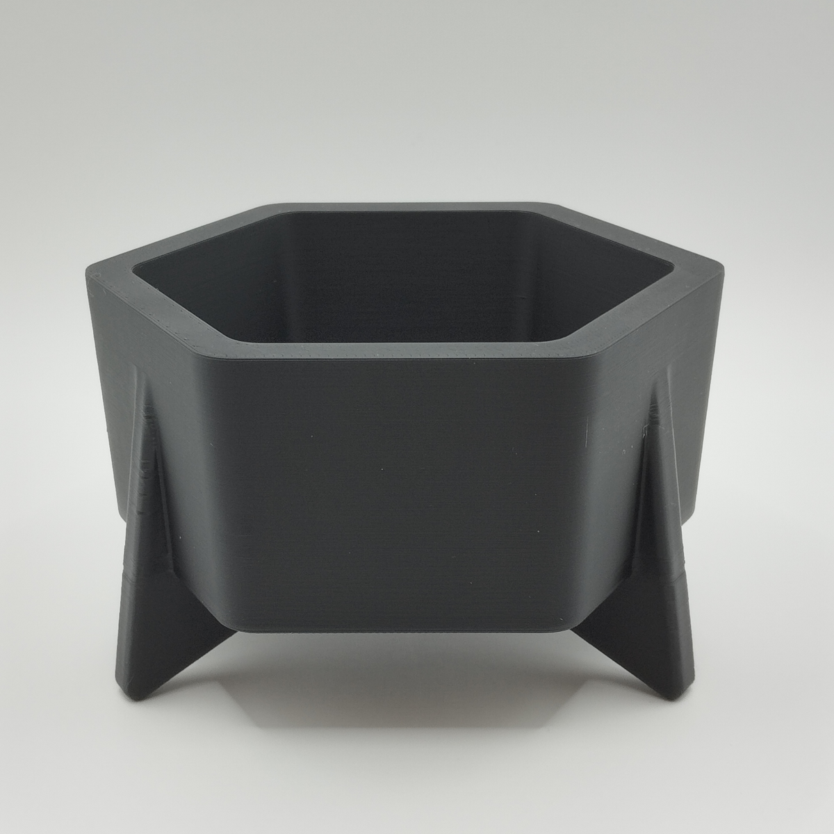 Pot de fleurs hexagonal style mid-century sur une étagère blanche avec petite plante grasse