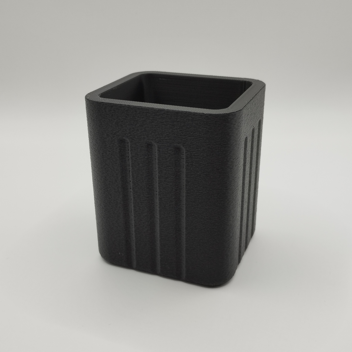 Pot à crayons minimaliste sur un bureau en bois avec des stylos et un carnet