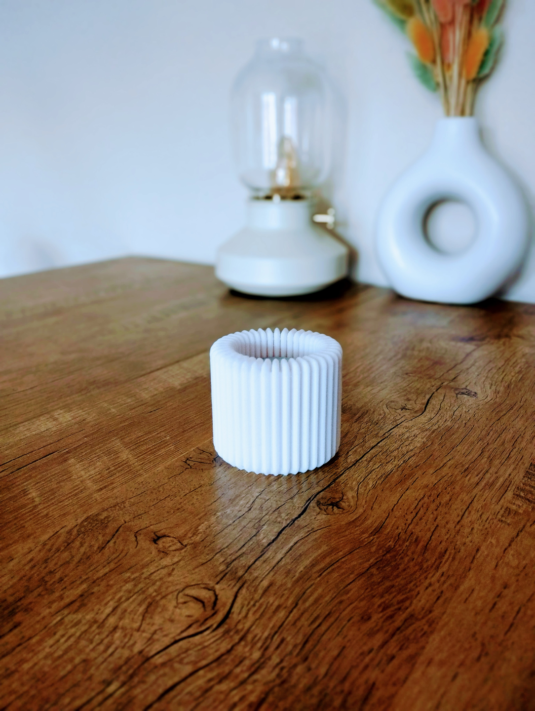 Photophore strié avec bougie LED allumée sur une étagère blanche