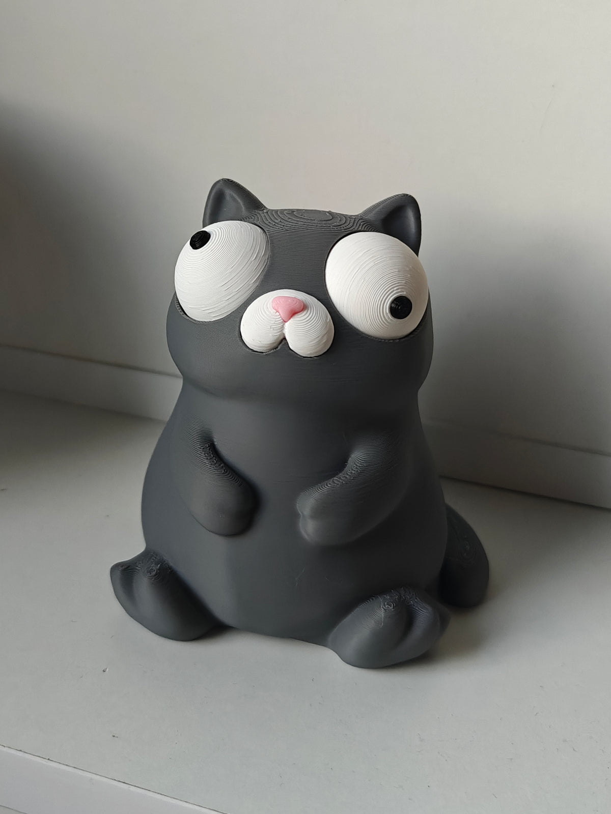Gros plan des yeux mobiles d'une figurine de chat rigolote à l'air perplexe