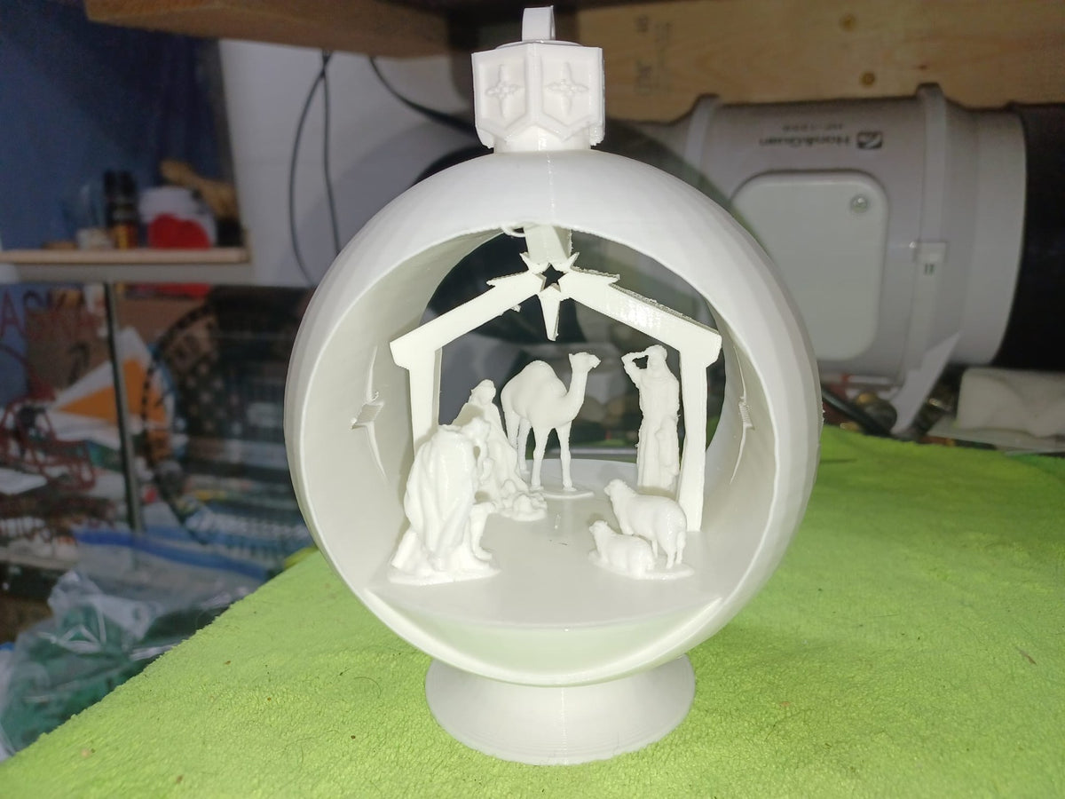 Crèche en forme de boule avec chameau, moutons et étoiles