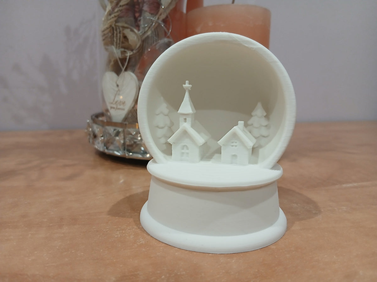 Village de Noël avec église, maison et sapins dans un cadre boule à neige