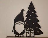 Figurine de lutin avec un cadeau au pied du sapin