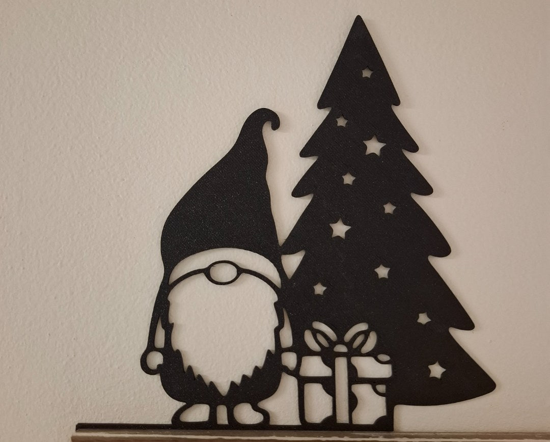 Figurine de lutin avec un cadeau au pied du sapin