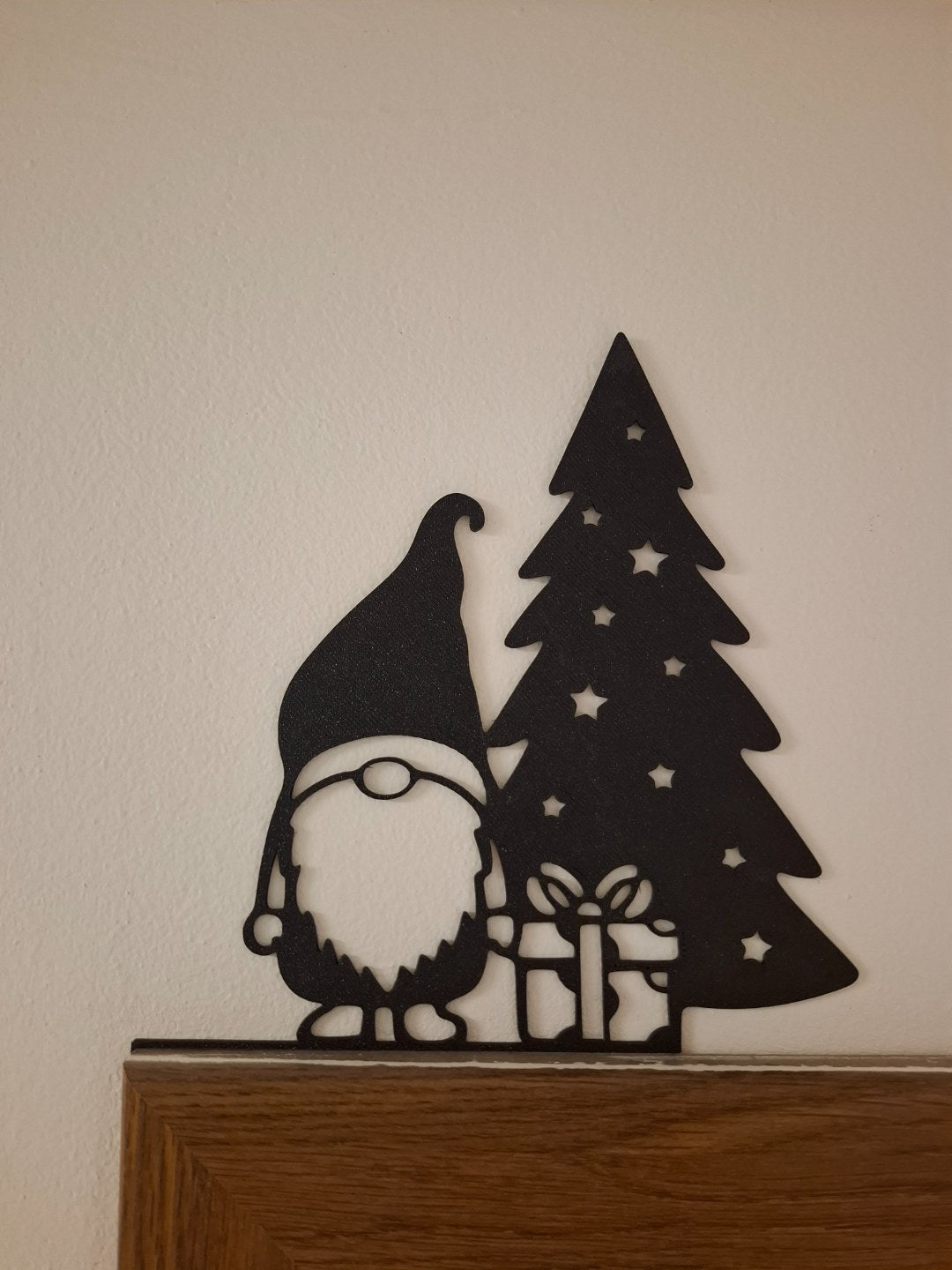 Figurine de lutin avec un cadeau au pied du sapin