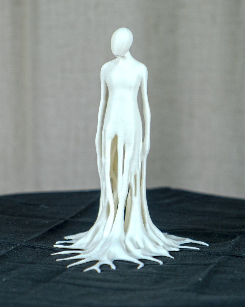 Gros plan d'une sculpture d'homme qui fond, à la forme fluide et dégoulinante, sur surface blanche