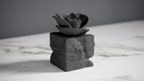 Eternal Bloom – sculpture de rose noire sur un bureau sombre près de livres
