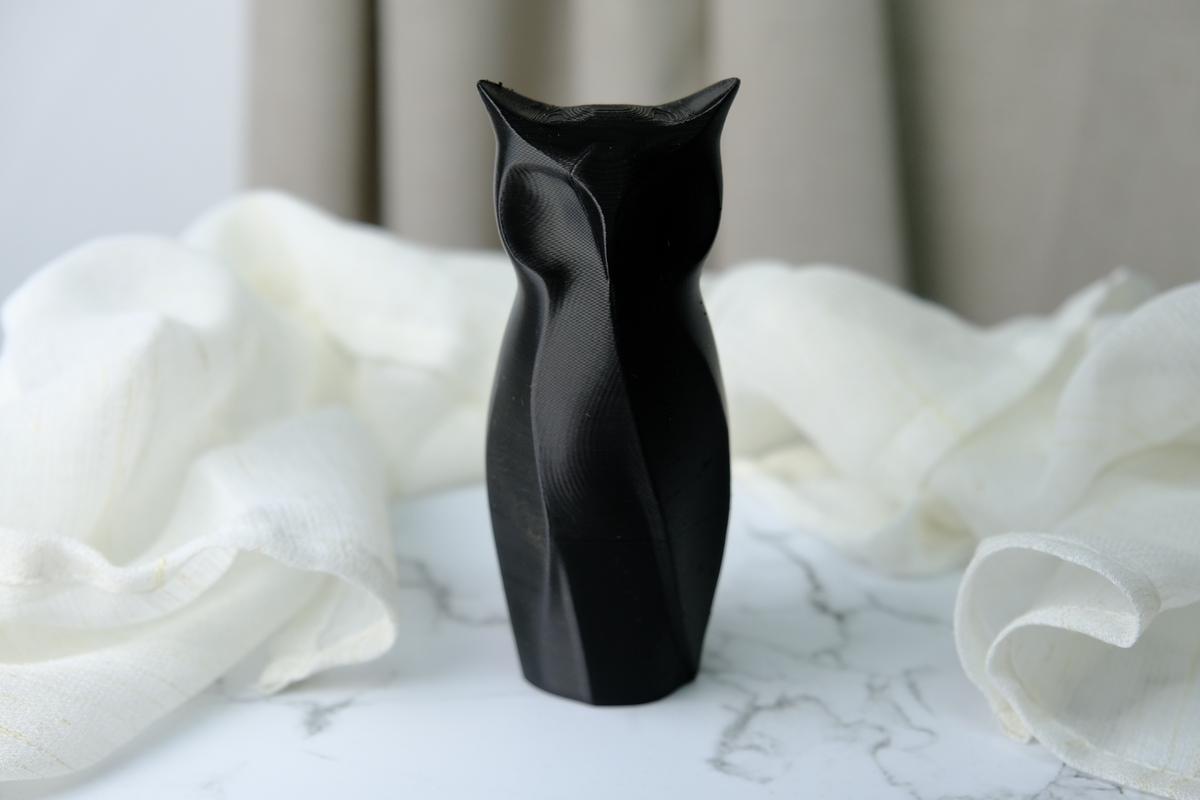 Sculpture géométrique de hibou sur un bureau minimaliste près d'une plante et d'un carnet