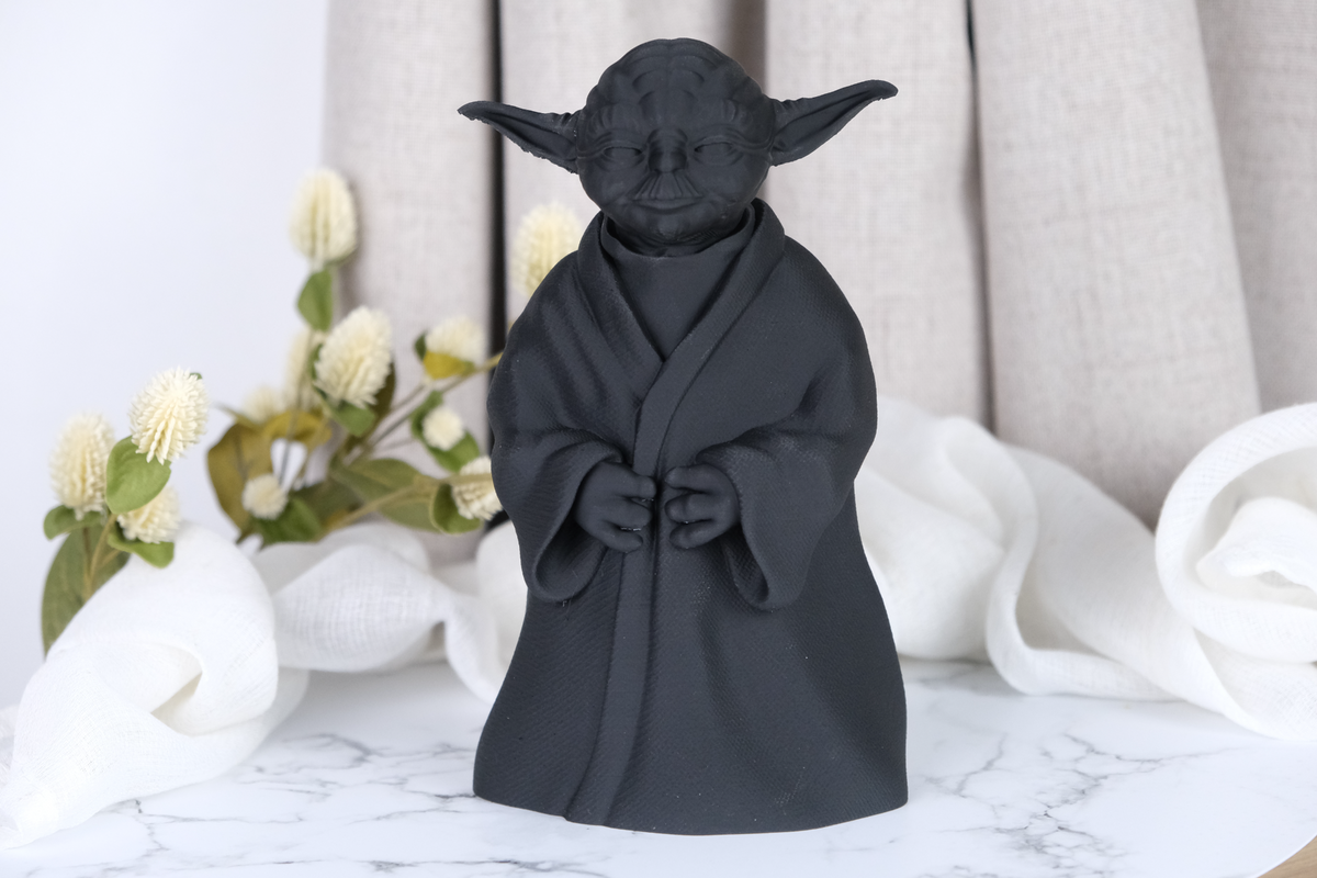 Sculpture Yoda sur un bureau en bois près d'une petite plante et d'une pile de livres