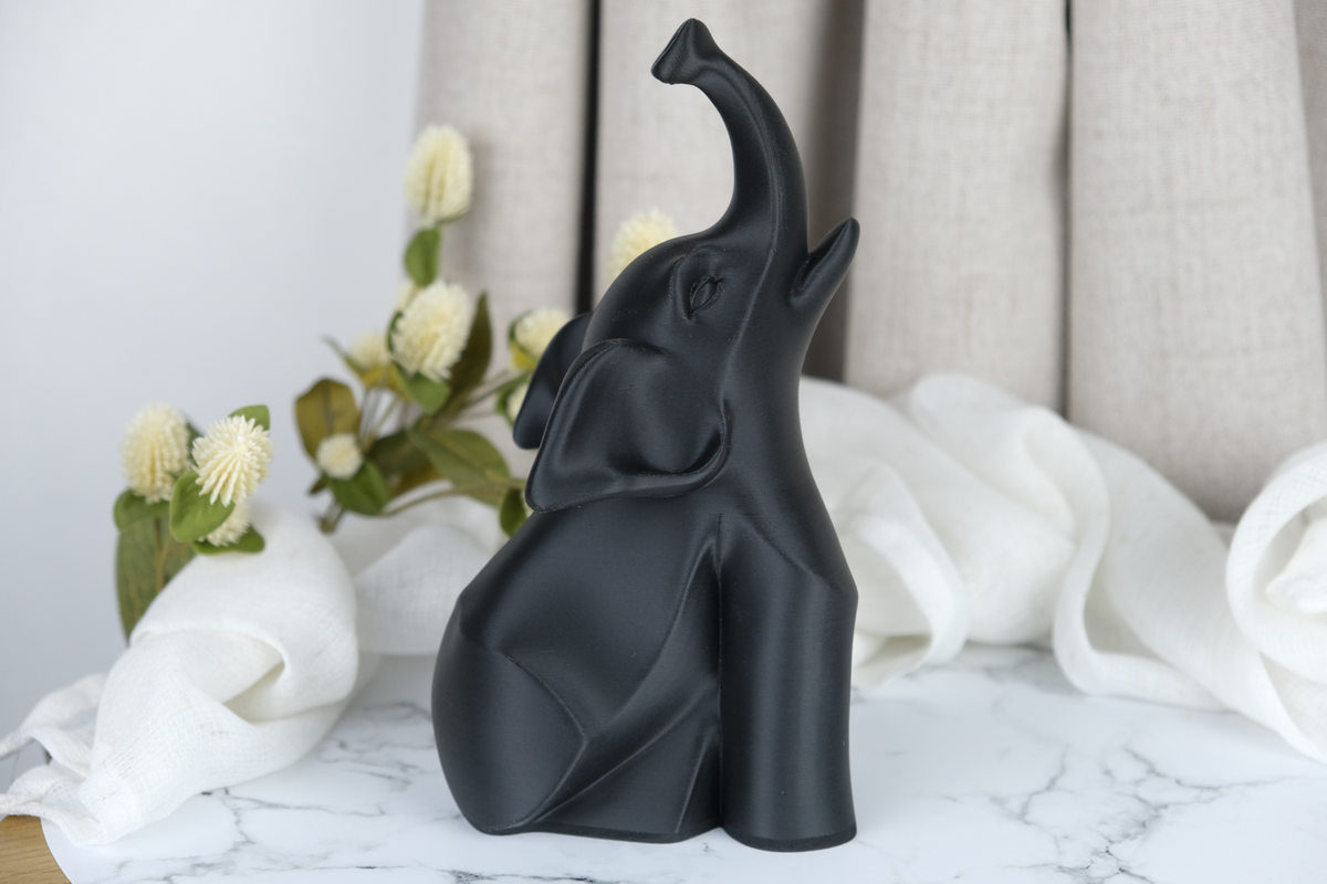 Sculpture moderne d'éléphant noir sur un bureau minimaliste près d'une bougie et d'une petite plante
