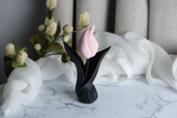 Sculpture de tulipe sur une étagère en bois près de petits objets en céramique en lumière naturelle
