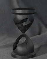 Sculpture noire de sablier brisé sur un bureau blanc