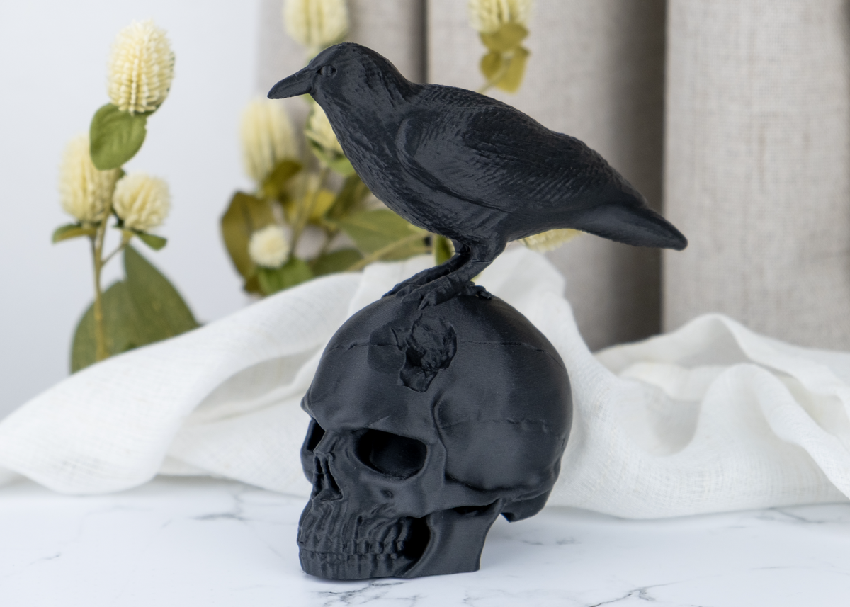 Sculpture de crâne de corbeau sur une étagère en bois foncé avec une bougie et des plantes séchées