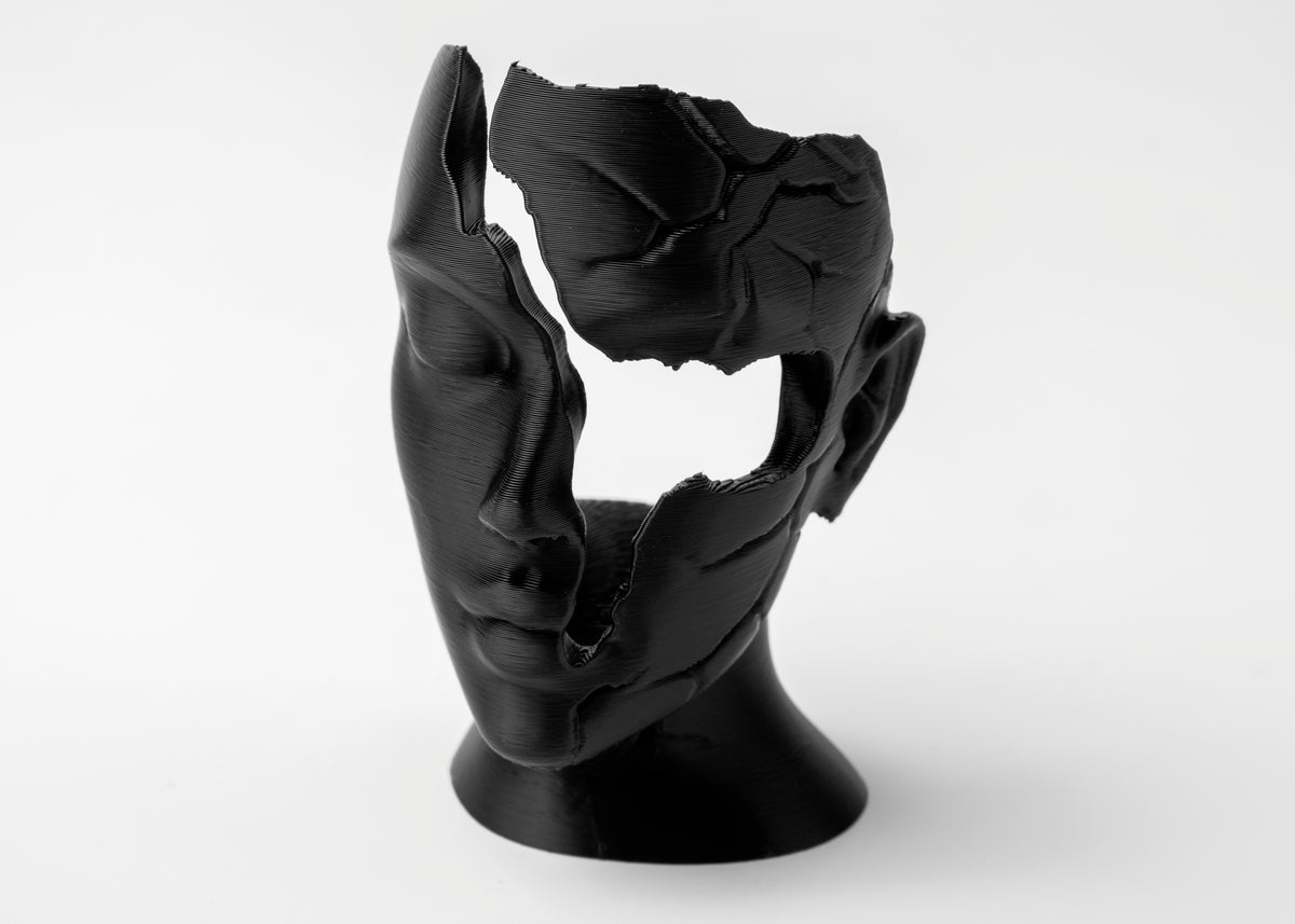 Visage féminin abstrait fragmenté en sculpture sur une étagère en bois près d'objets en céramique mate